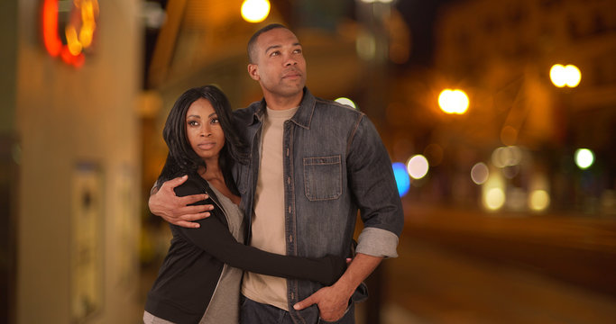 Young Millennial Black Couple Walking Together Along City Street Together At Night. African American Man And Woman In Love