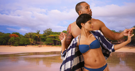 Two African American adults tango on the Costa Rican shore. A black couple dancing near the tropical ocean