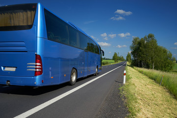 Blue bus traveling on asphalt road in a rural landscape © am