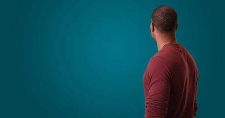 An African American man looks away from camera standing on a blue background. A black man with his...
