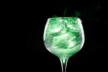 Splashing water in the wine glass with green background