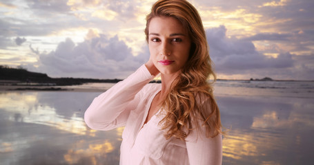 Beautiful woman standing at the beach looking at camera. Sexy woman in her 20s at the beach enjoying the view