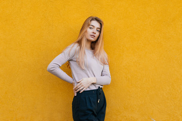 shapely beautiful blond girl walking, posing on a yellow background