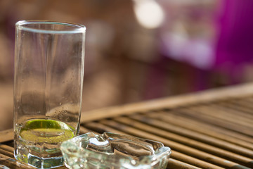 Empty glass with fresh lime  of cocktail and ashtray put on a bamboo table