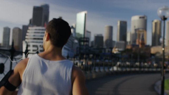 Camera follows behind a young athletic male jogging, in slow motion