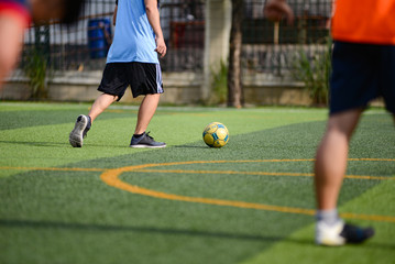 Unidentified group of male football players playing amateur football match on sunny summer day on simple sports venue