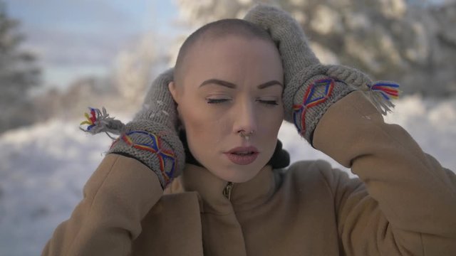 Young woman with shaved head poses during winter