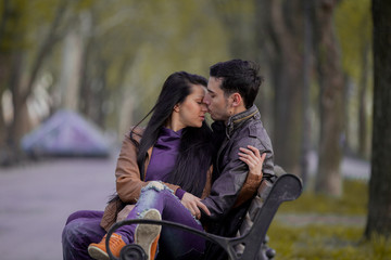 Fototapeta na wymiar Young couple kissing on the bench in springtime