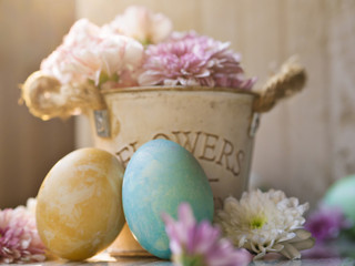 Close up of beautiful blue and yellow painting color decorated easter eggs with spring flowers pot on white wooden table with morning sunrise background for Easter day and Spring concept