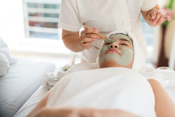 A female therapist doing Facial Spa/Treatment Add moisture to the skin with Asian woman lying on a bed in spa salon.