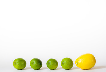 Row of four limes and a lemon isolated on white background