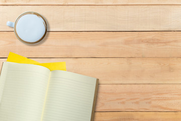 Empty book and hot coffee on wooden desk, copy space, mock up