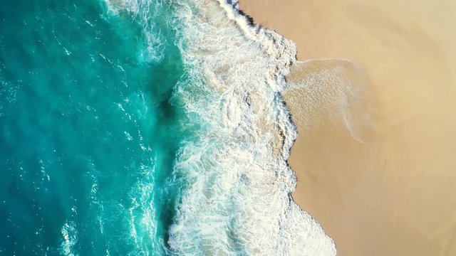 Aerial view waves break on white sand beach. Sea waves on the beautiful beach. drone 4k shot. zoom out