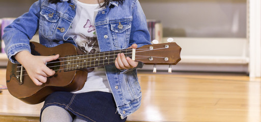 Little child playing ukulele in the library bossanova music in summer time, Cute girl play guitar vintage style, hand picking Guitar ,Ukulele on the library .