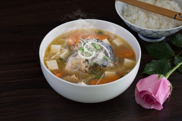 Japanese soup hot (Miso) with head salmon in white bowl on brown wooden table, Decoration with pink rose