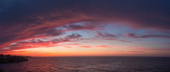 Naklejka na ściany i meble Drone aerial view of a Fiery sunrise with multicolored clouds. Mallorca Island, Spain. Summer season