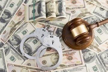 handcuffs, judge's hammer against the background of dollar bills.