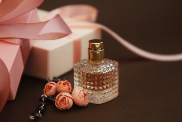 Women's Pink Perfume in Beautiful Bottle and Artificialt Flowers Bracelet on Brown Background with gift boxes on Background.