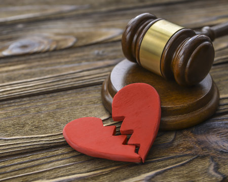 figure of a broken red heart, gavel, hammer of a judge on a wooden background.