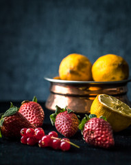strawberry and lemons in dark setting