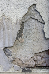 abfallender Putz mit Rissen in mehreren Schichten an Hausmauer Sanierungsbedarf, sloping plaster with cracks in several layers on house wall renovation needs