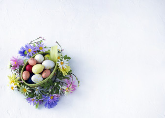 Easter composition: on a white background basket with Easter eggs, feathers and Easter decor