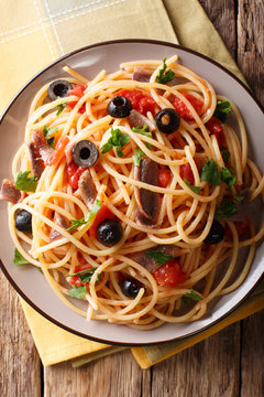 Pasta Alla Puttanesca with anchovies and black olives. Vertical top view