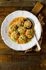 Meatballs stewed with tomato sauce in a plate on a wooden table