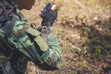 Closeup image of an armed soldier holding and using radio communication in the battle field