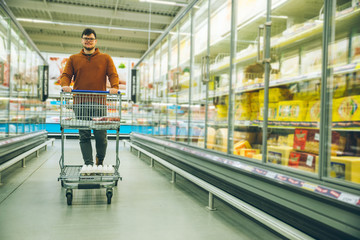 man walk with cart between rows with refrigerators.