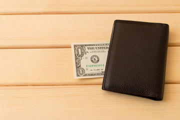 Leather wallet with dollars on wooden table background