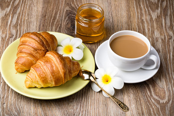Cup of coffee and croissants on wooden background