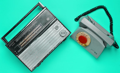 Culture of the 70s. Radio receiver and rotary telephone on blue background. Retro devices. Top view.