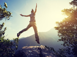 hipster woman hiker jumping on cliff's edge