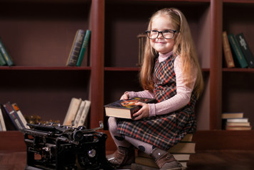 Little Girl in the library on the background of bookshelves
