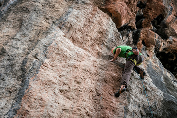 bald man climbs rock, side view, Turkey