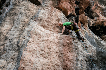 bald man climbs rock, side view, Turkey
