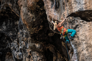 Blonde girl climbs rock tufa, side view, Turkey