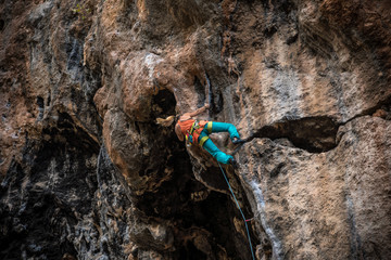 Blonde girl climbs rock tufa, side view, Turkey