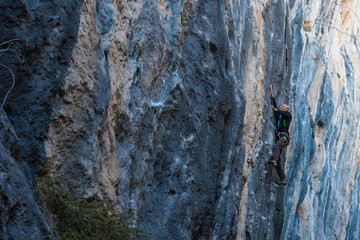 Men climbs a rock with a rope, lead, side view. Turkey