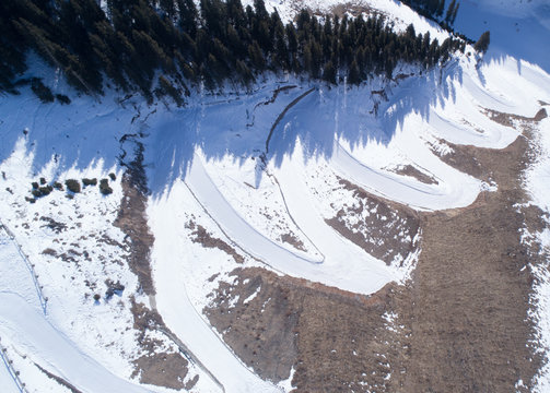 Aerial view of the curving alpine skiing and snowboarding piste in mountains