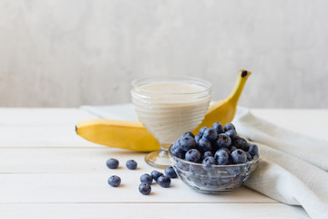 Banana smoothies and blueberries on a white table. 