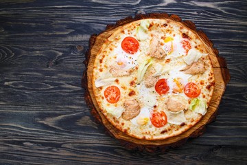 Appetizing caesar pizza with cherry tomatoes, grilled chicken, lettuce and quail eggs, top view. American recipe, restaurant menu photo