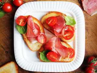 Bruschetta with prosciutto ham, cherry tomatoes and green spinach . Top view