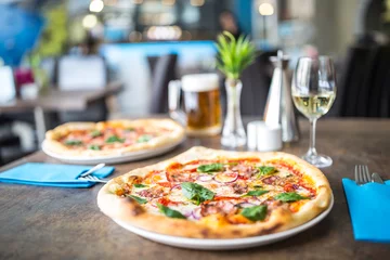 Foto op Plexiglas De geserveerde eettafel met pizza in pizzeria of restaurant. © weyo
