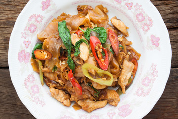Spicy stir-fried flat noodles on wooden background, Top view, Thai food