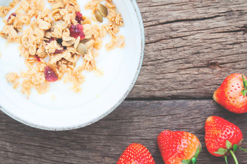 Yogurt with granola on top in a bowl and strawberries on wooden table, Healthy and Diet concept