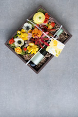 Fototapeta na wymiar Bouquet of flowers with bottle of white wine in old wooden rustic box. Romantic present, beautiful floral arrangement