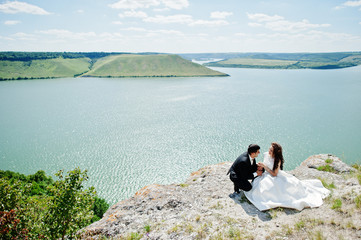 Fototapeta na wymiar Wedding couple at breathtaking landscape with rock and lake.