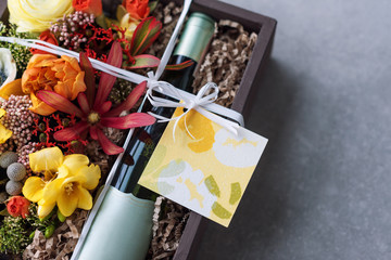 Bouquet of flowers with bottle of white wine in old wooden rustic box. Romantic present, beautiful floral arrangement